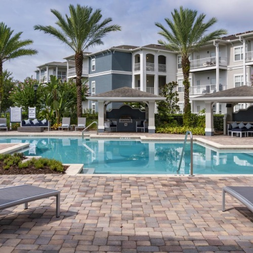 Resort-style swimming pool a pool with chairs and a building in the background